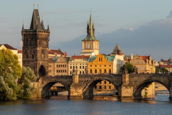 Pont Charles avec le château de Prague et la cathédrale Saint-Guy illuminés au crépuscule, reflets sur la Vltava