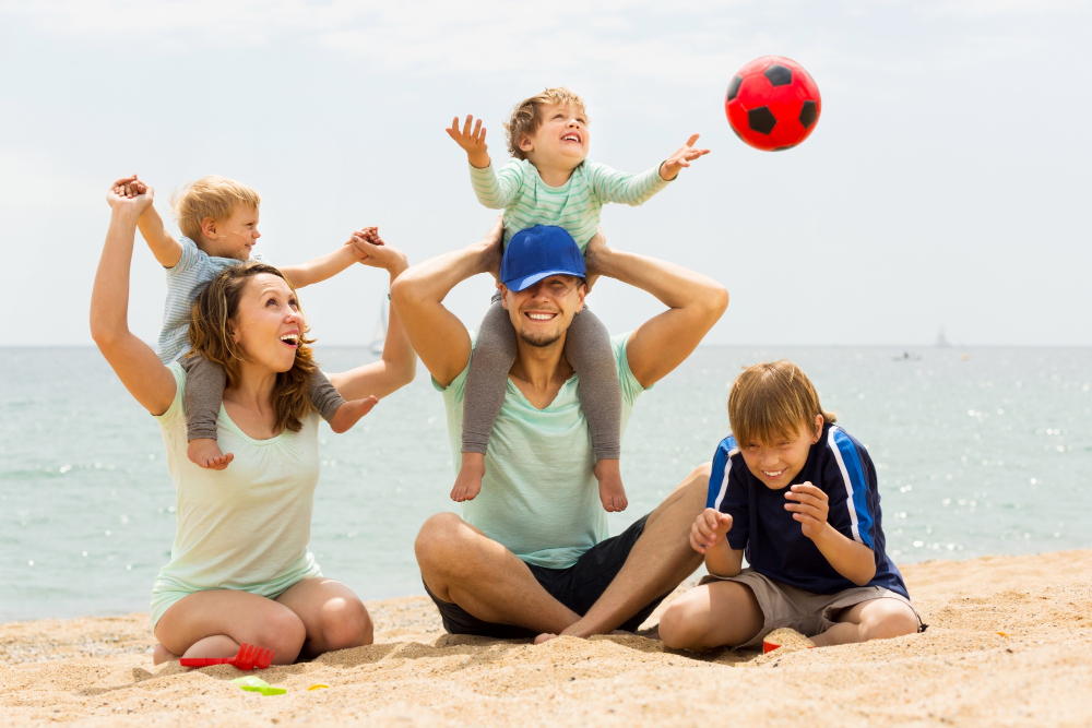 famille heureuse composée d'un couple et de trois enfants jouent sur la plage