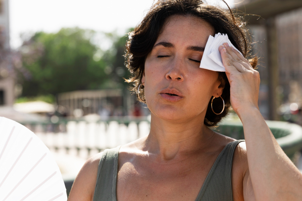 Femme se rafraîchissant avec un éventail pendant une canicule en ville