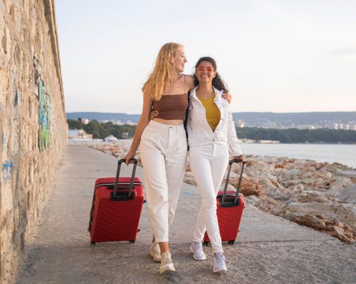 Deux jeune-femmes en vacances tirent leurs valises à roulettes