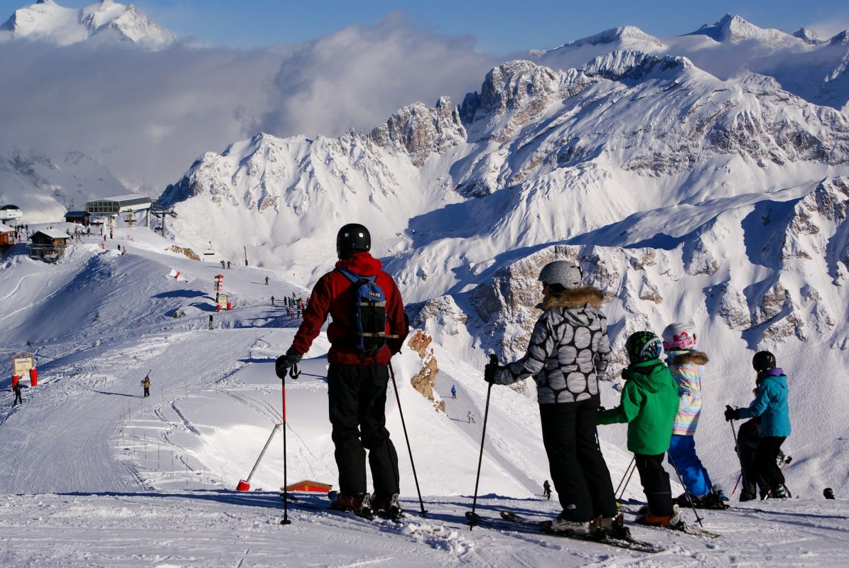 Famille de skieurs avec enfants admirant les sommets enneigés en haut d'une piste