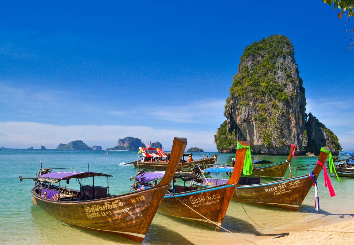 Bateaux longue-queue sur la plage de Phra Nang à Railay, face à un piton calcaire, à Krabi en Thaïlande